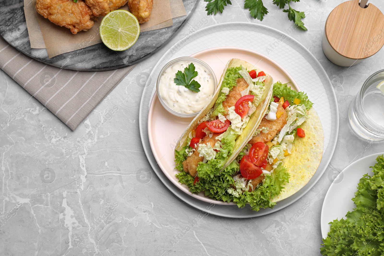 Delicious fish tacos served on grey marble table, flat lay Photo of Delicious fish tacos served on grey marble table, flat lay