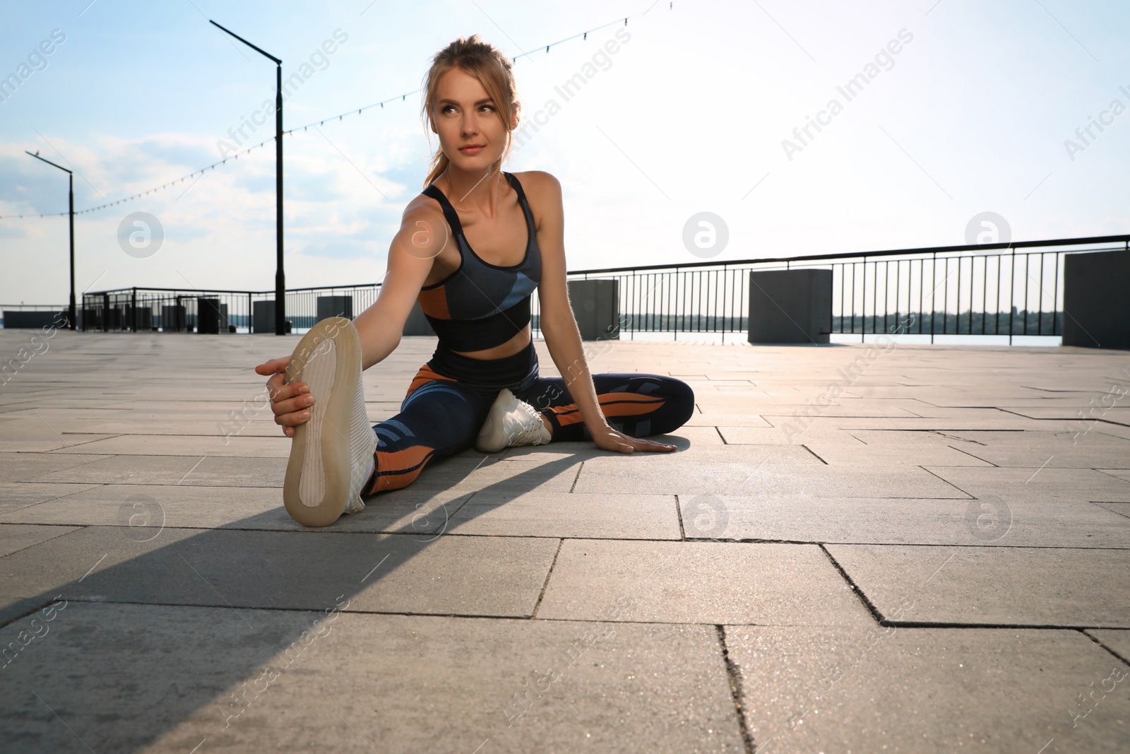 Beautiful woman in sportswear doing exercises outdoors on sunny day Photo of Beautiful woman in sportswear doing exercises outdoors on sunny day