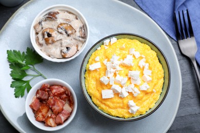 Tasty banosh served with brynza, pork cracklings and mushrooms on dark table, flat lay. Traditional Ukrainian dish Photo of Tasty banosh served with brynza, pork cracklings and mushrooms on dark table, flat lay. Traditional Ukrainian dish