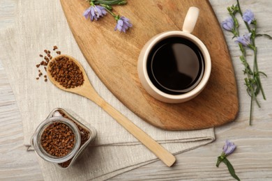 Cup of delicious chicory drink, granules and flowers on white wooden table, flat lay Photo of Cup of delicious chicory drink, granules and flowers on white wooden table, flat lay