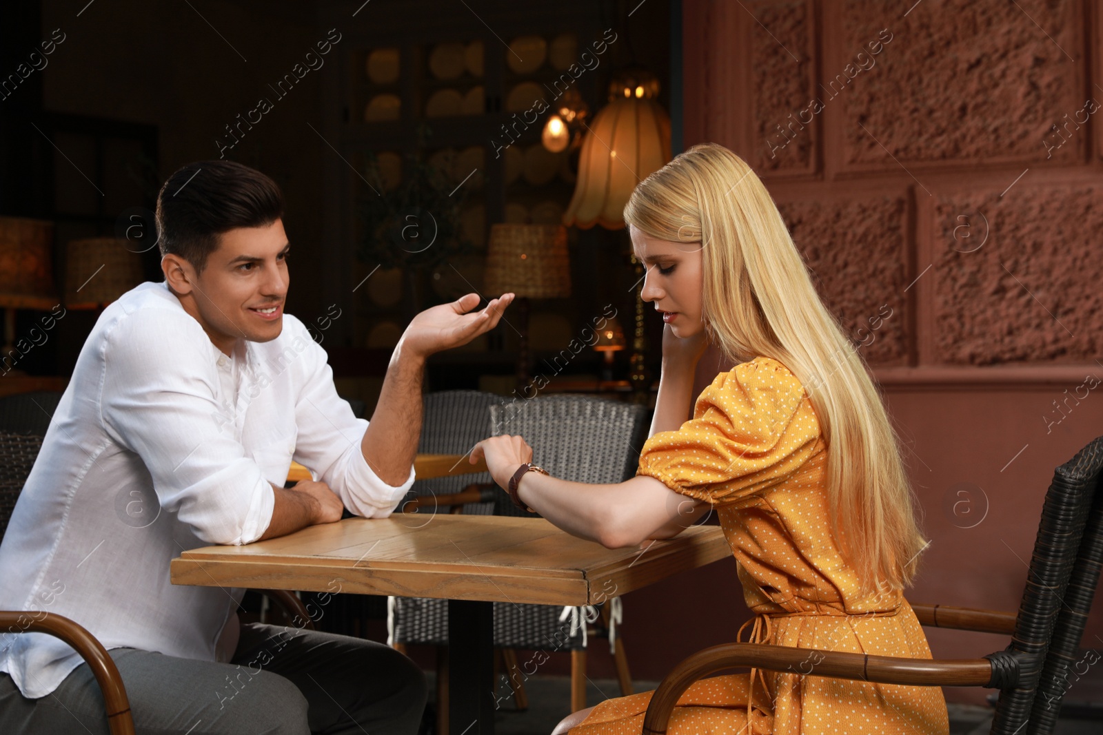 Young woman checking time during boring date in outdoor cafe Photo of Young woman checking time during boring date in outdoor cafe