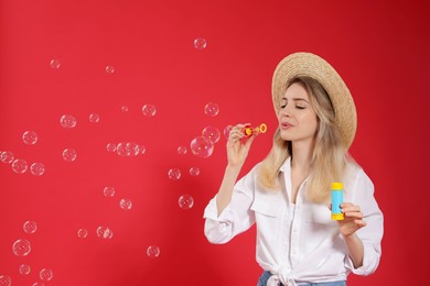 Young woman blowing soap bubbles on red background, space for text Photo of Young woman blowing soap bubbles on red background, space for text