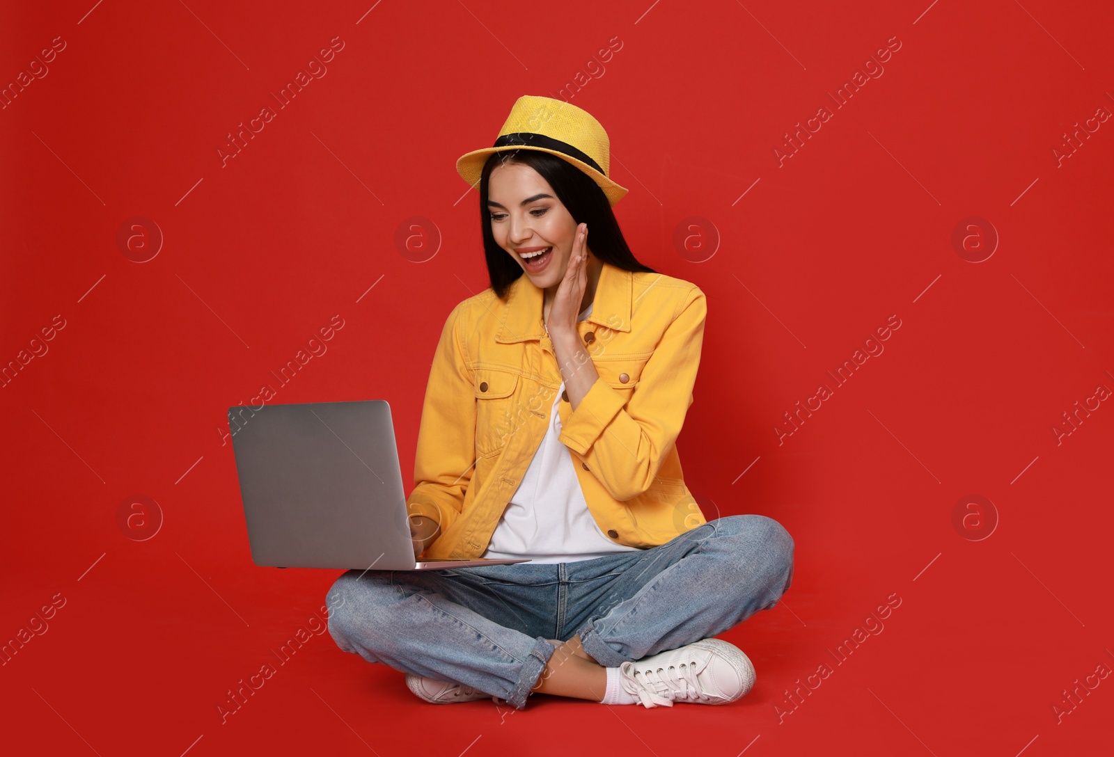 Emotional young woman with modern laptop on red background. Space for text Photo of Emotional young woman with modern laptop on red background. Space for text