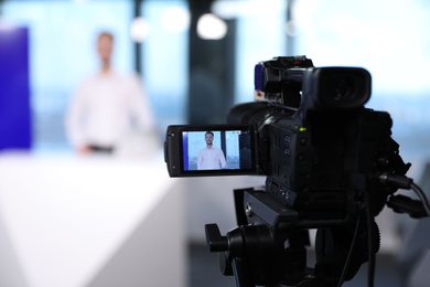 Photo of Presenter working in studio, focus on video camera