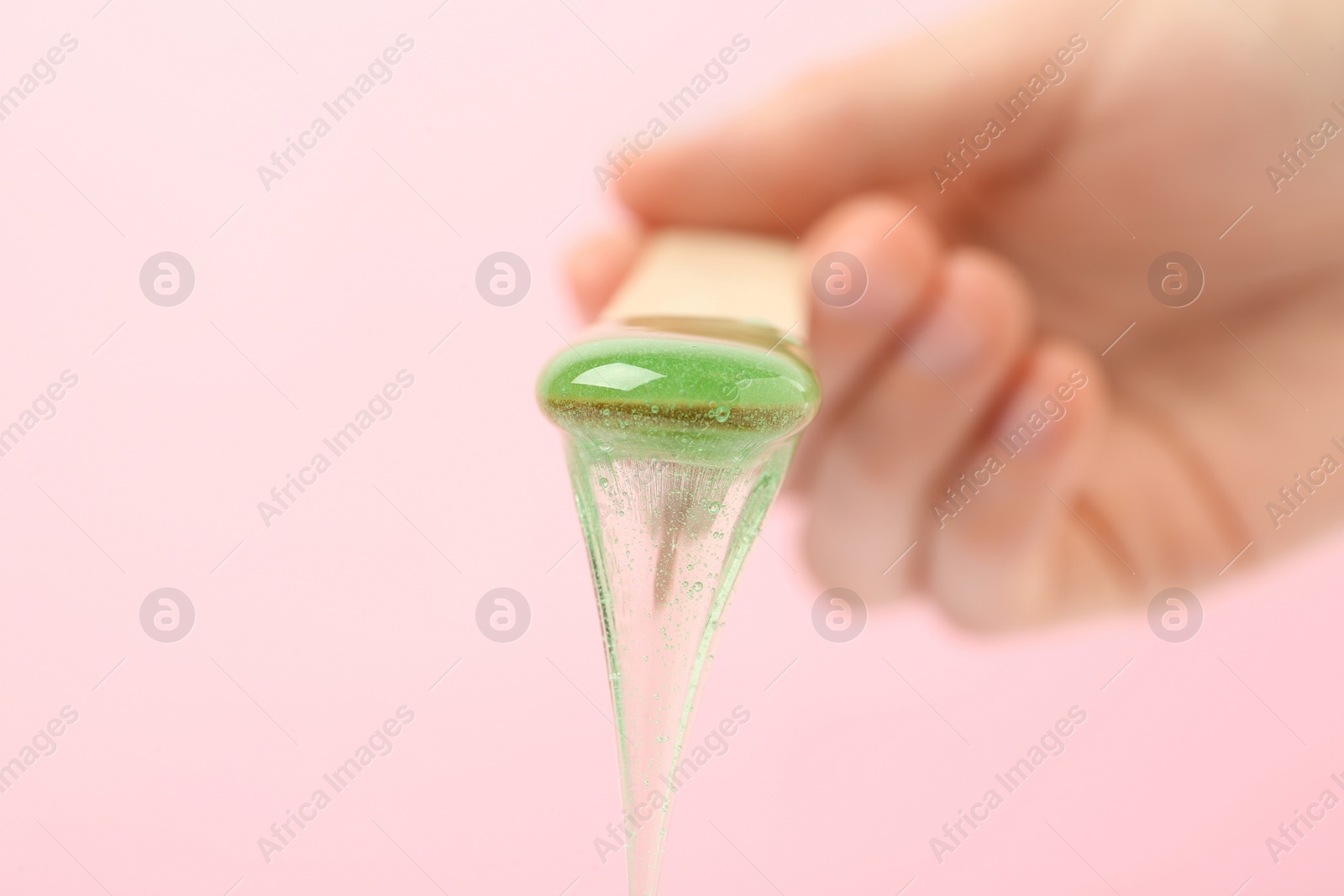 Photo of Woman holding spatula with hot depilatory wax on light background, closeup