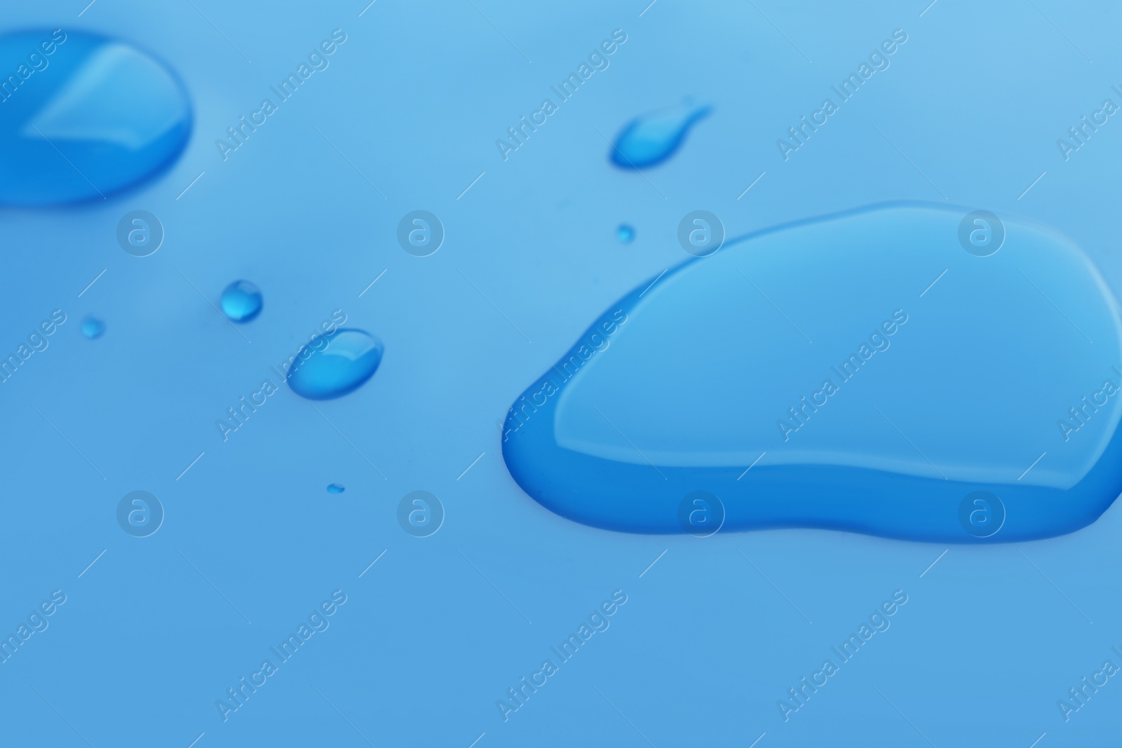 Drops of spilled water on blue background, closeup Photo of Drops of spilled water on blue background, closeup