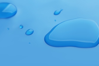 Drops of spilled water on blue background, closeup Photo of Drops of spilled water on blue background, closeup