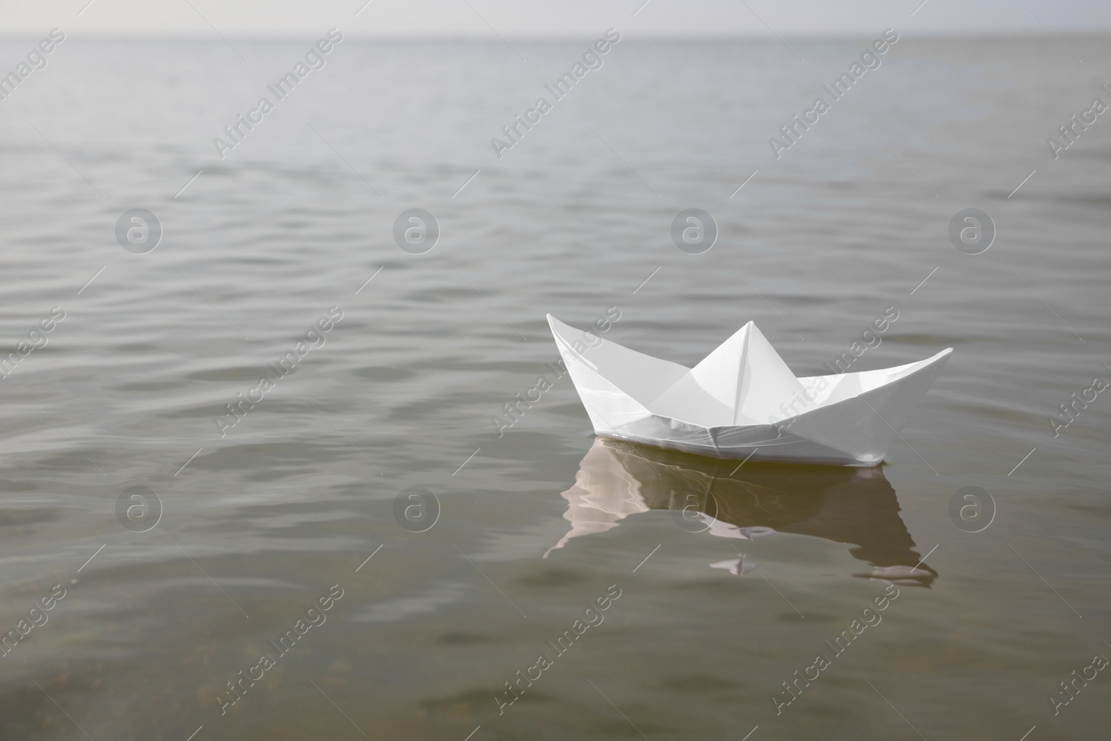 White paper boat on water surface, space for text Photo of White paper boat on water surface, space for text