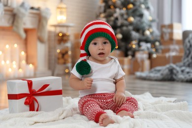 Cute little baby with elf hat near Christmas gift on floor at home Image of Cute little baby with elf hat near Christmas gift on floor at home