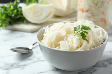 Tasty fermented cabbage on white marble table, closeup Photo of Tasty fermented cabbage on white marble table, closeup