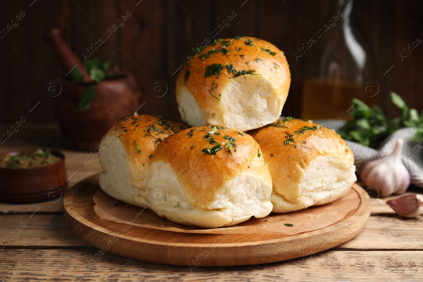 Traditional pampushka buns with garlic and herbs on wooden table Photo of Traditional pampushka buns with garlic and herbs on wooden table