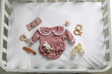 Flat lay composition with cute baby clothes and accessories on white bedsheet in crib Photo of Flat lay composition with cute baby clothes and accessories on white bedsheet in crib