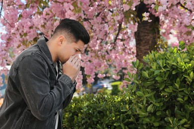 Man suffering from seasonal pollen allergy near blossoming tree outdoors Photo of Man suffering from seasonal pollen allergy near blossoming tree outdoors