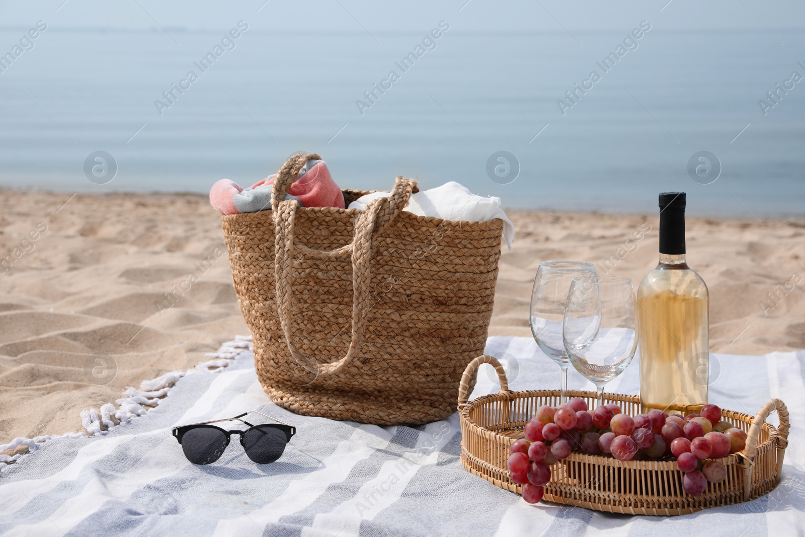 Bag, blanket, wine and other stuff for beach picnic on sandy seashore Photo of Bag, blanket, wine and other stuff for beach picnic on sandy seashore