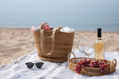 Bag, blanket, wine and other stuff for beach picnic on sandy seashore Photo of Bag, blanket, wine and other stuff for beach picnic on sandy seashore