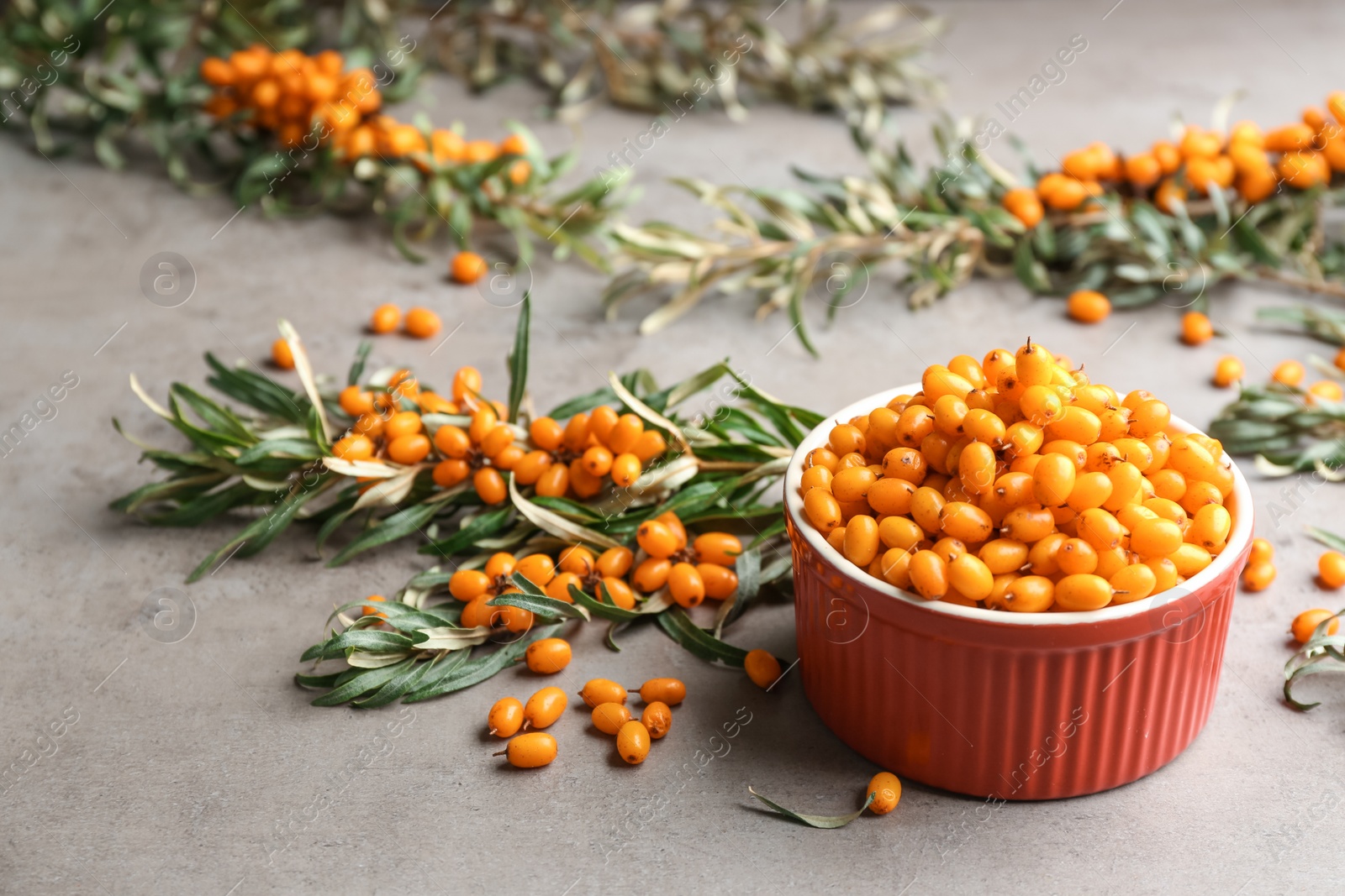 Fresh ripe sea buckthorn in bowl on grey table Photo of Fresh ripe sea buckthorn in bowl on grey table