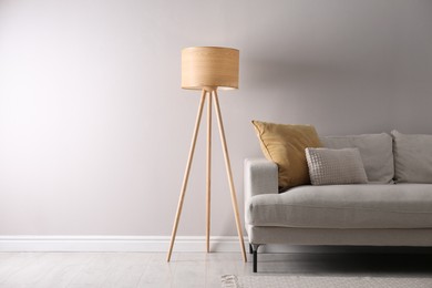 Stylish living room interior with comfortable sofa and tripod floor lamp. Space for text Photo of Stylish living room interior with comfortable sofa and tripod floor lamp. Space for text