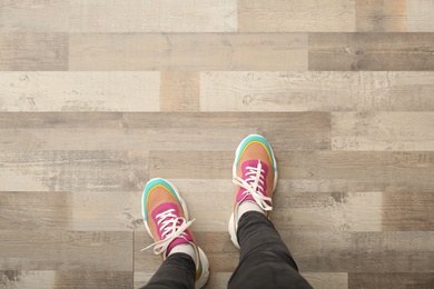 Woman in colorful sneakers standing on wooden floor, top view. Space for text Photo of Woman in colorful sneakers standing on wooden floor, top view. Space for text