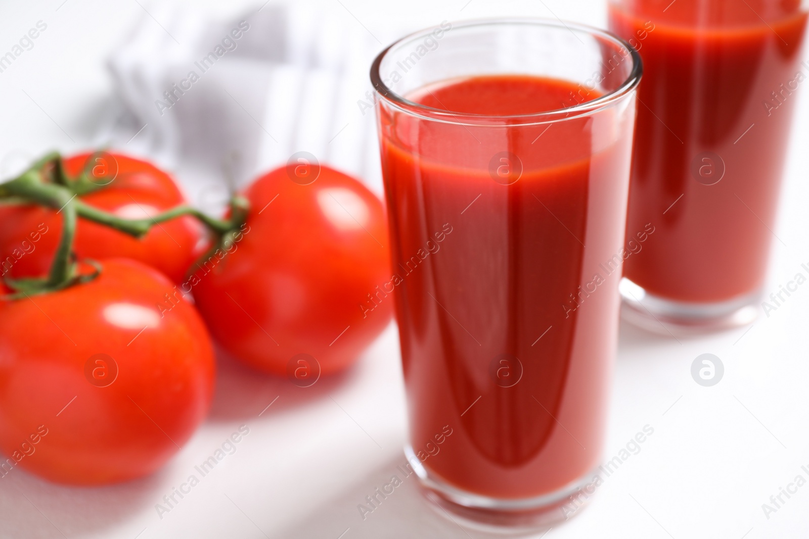 Delicious fresh tomato juice on white table, closeup Photo of Delicious fresh tomato juice on white table, closeup