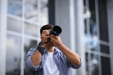 Photographer taking picture with professional camera on city street Photo of Photographer taking picture with professional camera on city street