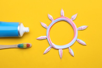 Sun made with toothpaste, brush and tube on yellow background, flat lay Photo of Sun made with toothpaste, brush and tube on yellow background, flat lay