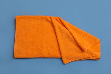 Folded orange beach towel on blue background, top view Photo of Folded orange beach towel on blue background, top view