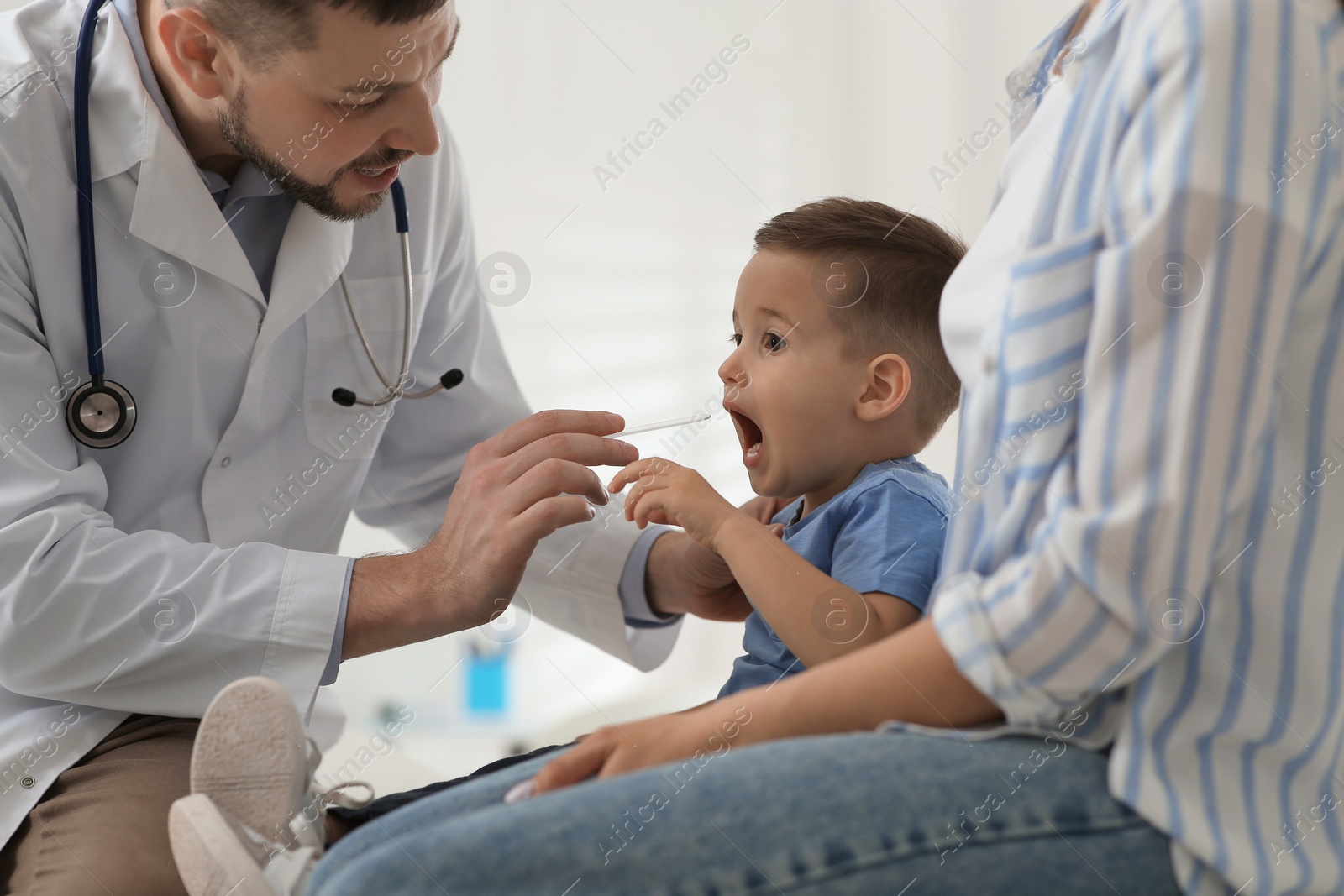 Mother and son visiting pediatrician in hospital. Doctor examining little boy Photo of Mother and son visiting pediatrician in hospital. Doctor examining little boy
