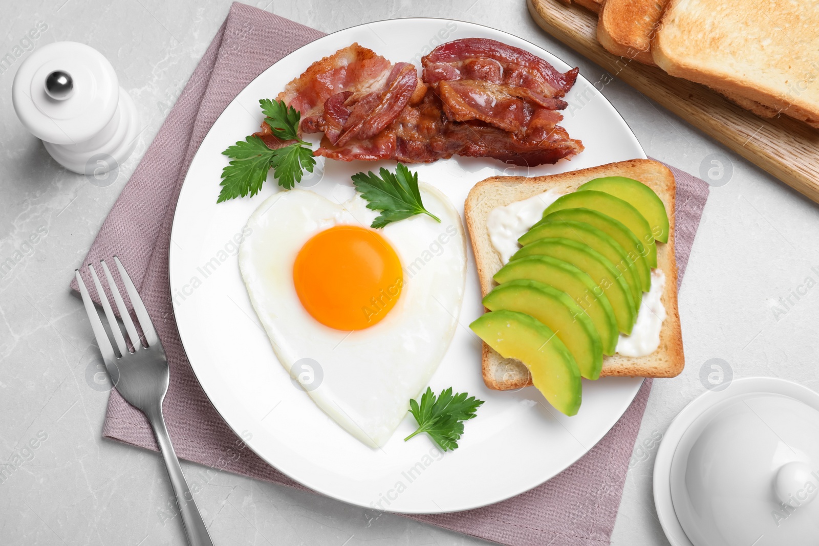 Romantic breakfast with fried bacon, heart shaped egg and avocado toast on light grey table, flat lay. Valentine's day celebration Photo of Romantic breakfast with fried bacon, heart shaped egg and avocado toast on light grey table, flat lay. Valentine's day celebration