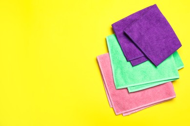 Colorful microfiber cloths on yellow background, flat lay. Space for text Photo of Colorful microfiber cloths on yellow background, flat lay. Space for text