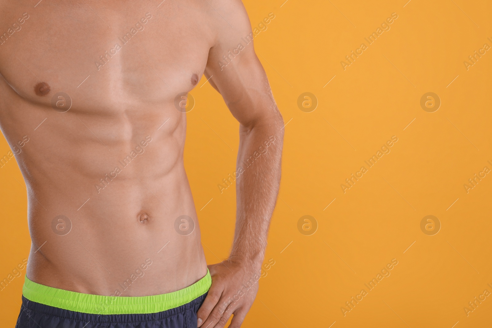 Shirtless man with slim body on yellow background, closeup. Space for text Photo of Shirtless man with slim body on yellow background, closeup. Space for text