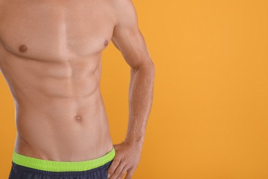 Shirtless man with slim body on yellow background, closeup. Space for text Photo of Shirtless man with slim body on yellow background, closeup. Space for text