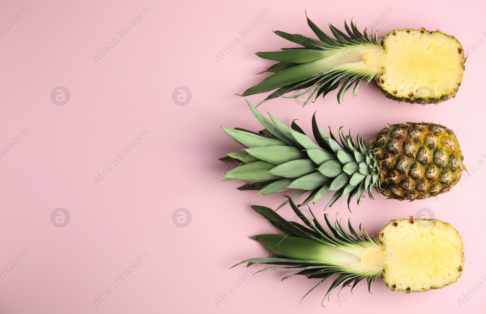 Whole and cut pineapples on pink background, flat lay. Space for text Photo of Whole and cut pineapples on pink background, flat lay. Space for text