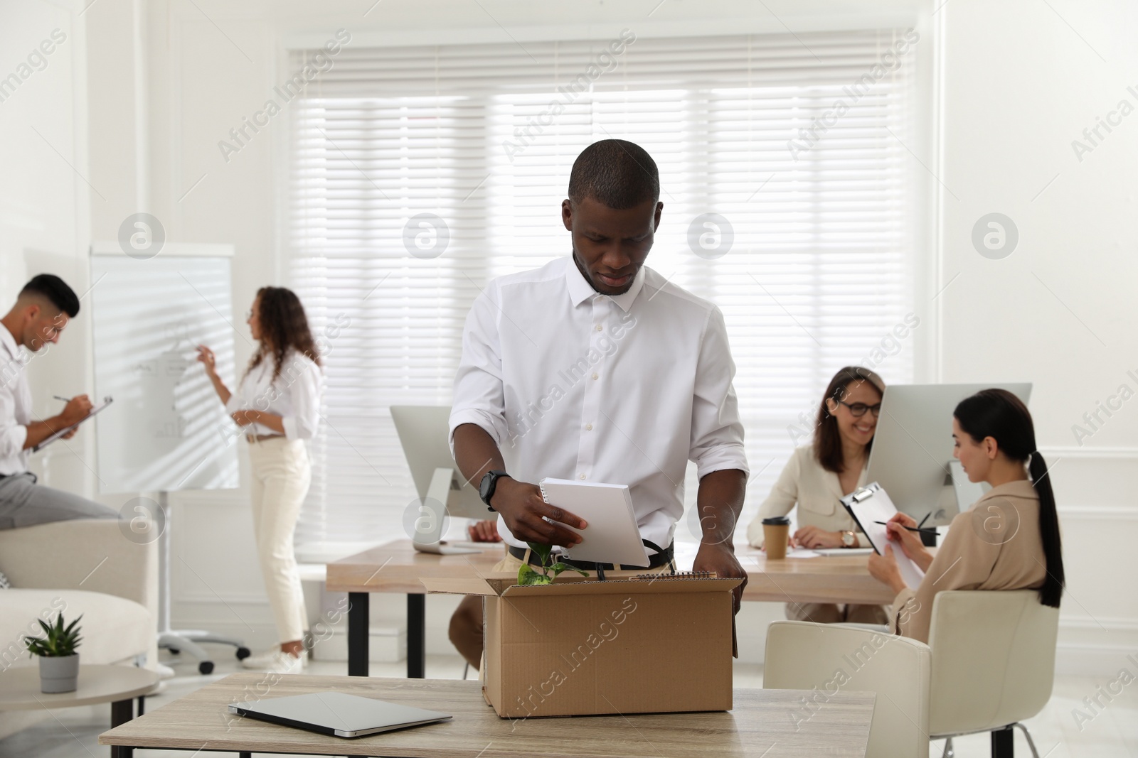 New coworker unpacking box with personal items at workplace in office Photo of New coworker unpacking box with personal items at workplace in office