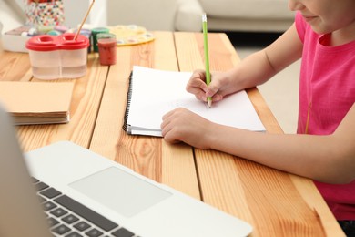 Little girl drawing on paper with pencil at online lesson indoors, closeup. Distance learning Photo of Little girl drawing on paper with pencil at online lesson indoors, closeup. Distance learning