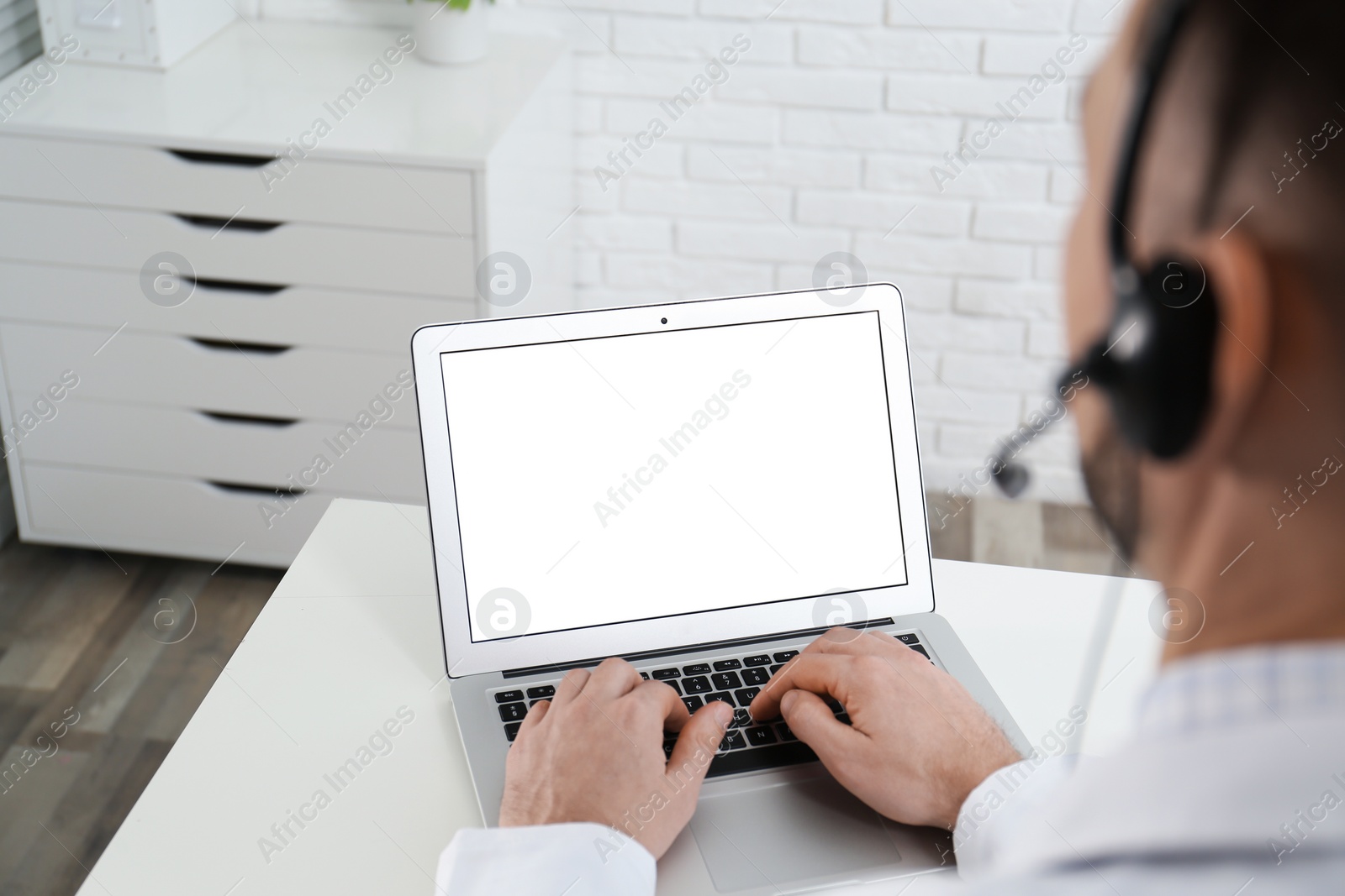 Doctor with headset consulting patient online at desk in clinic, space for text. Health service hotline Photo of Doctor with headset consulting patient online at desk in clinic, space for text. Health service hotline