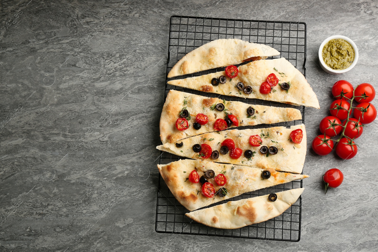 Delicious focaccia bread with olives and tomatoes on grey table, flat lay. Space for text Photo of Delicious focaccia bread with olives and tomatoes on grey table, flat lay. Space for text