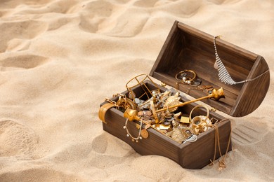 Open wooden treasure chest on sand, space for text Photo of Open wooden treasure chest on sand, space for text