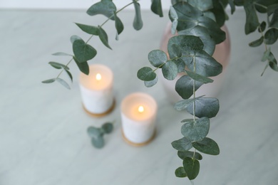 Beautiful eucalyptus branches and burning candles on grey table, closeup. Interior element Photo of Beautiful eucalyptus branches and burning candles on grey table, closeup. Interior element