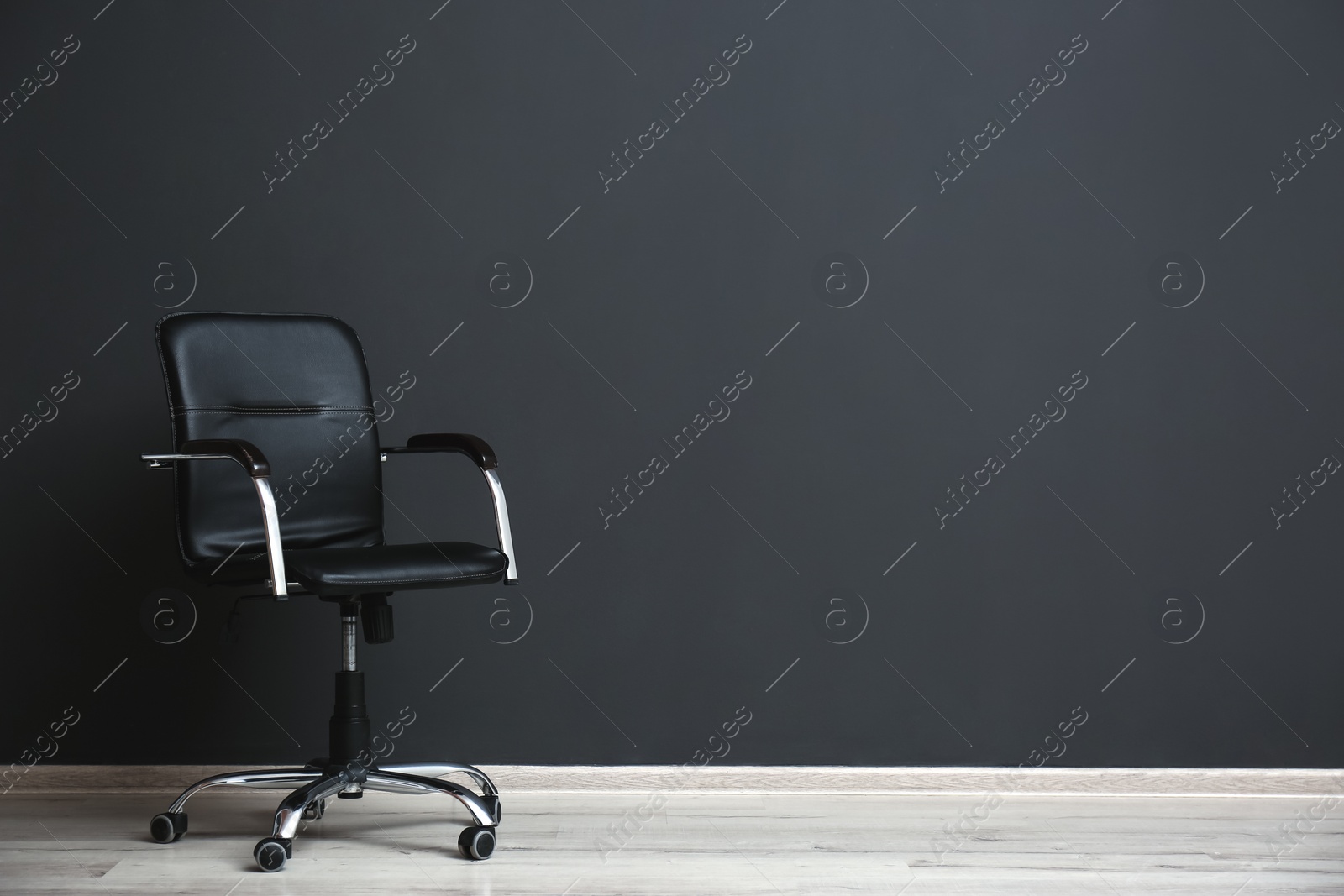 Comfortable office chair near black wall indoors. Space for text Photo of Comfortable office chair near black wall indoors. Space for text