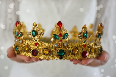 Woman holding beautiful crown with gems on light background, closeup. Fantasy medieval period Photo of Woman holding beautiful crown with gems on light background, closeup. Fantasy medieval period