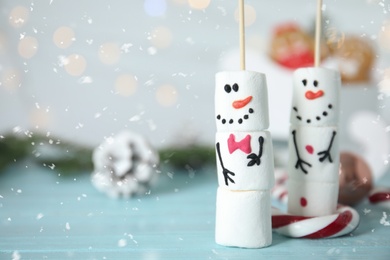 Funny snowmen made of marshmallows on light blue wooden table, closeup. Space for text Photo of Funny snowmen made of marshmallows on light blue wooden table, closeup. Space for text