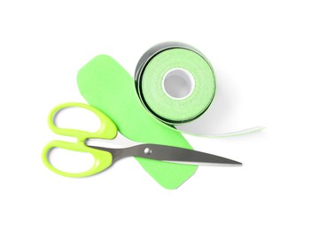 Scissors, bright kinesio tape roll and piece on white background, top view Photo of Scissors, bright kinesio tape roll and piece on white background, top view