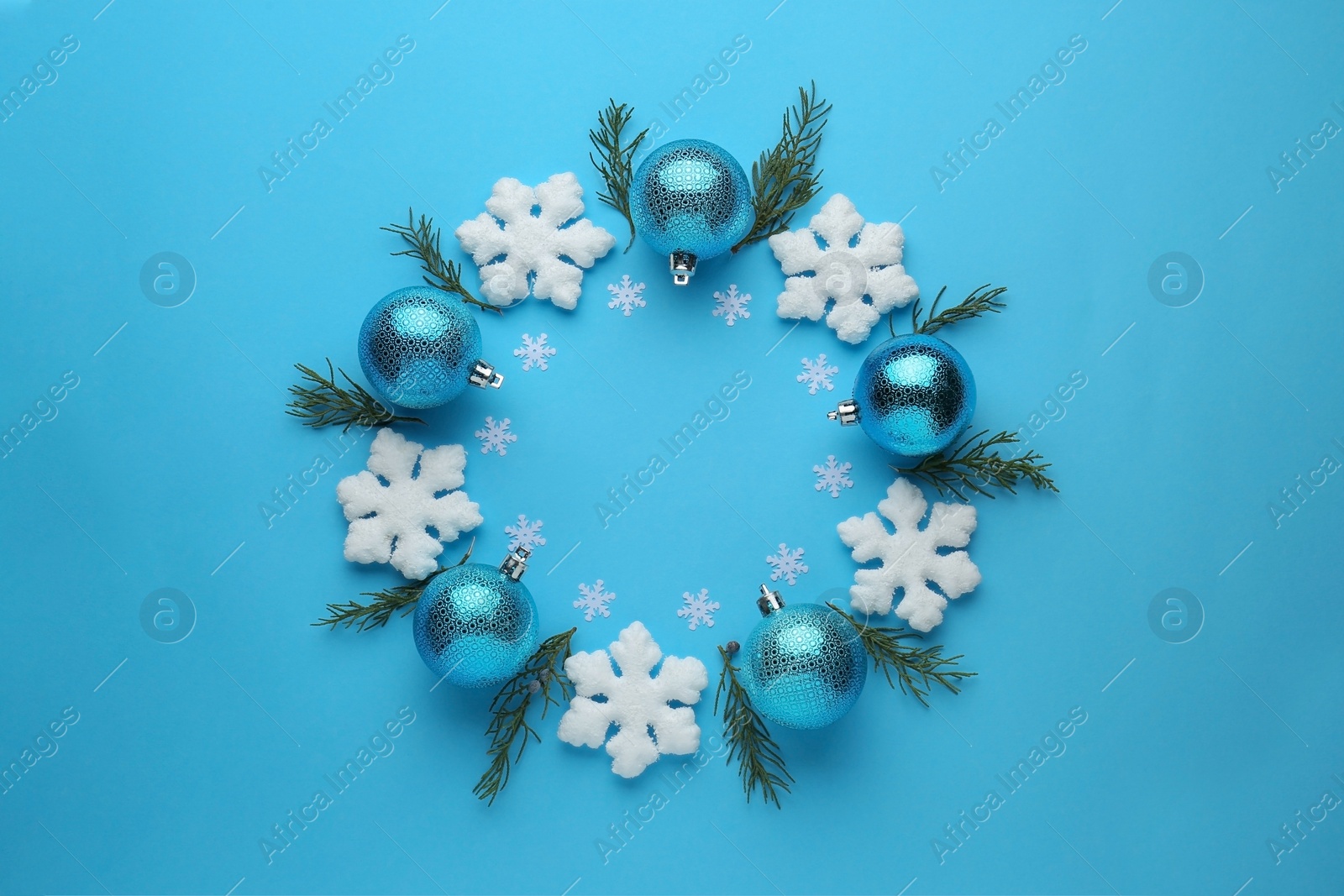 Bright festive wreath made of Christmas balls, decorative snowflakes and fir branches on light blue background, top view. Space for text Photo of Bright festive wreath made of Christmas balls, decorative snowflakes and fir branches on light blue background, top view. Space for text
