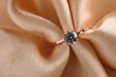 Beautiful engagement ring with gemstone on beige fabric, top view Photo of Beautiful engagement ring with gemstone on beige fabric, top view