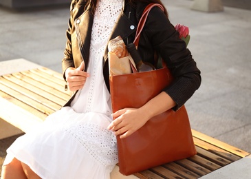 Woman with leather shopper bag sitting on bench, closeup Photo of Woman with leather shopper bag sitting on bench, closeup