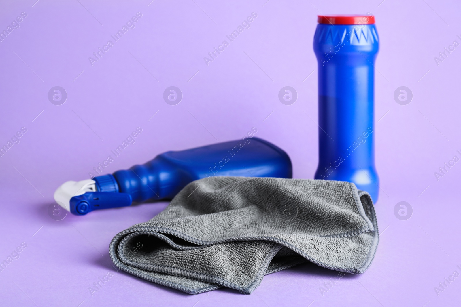 Grey microfiber cloth and detergents on light background Photo of Grey microfiber cloth and detergents on light background