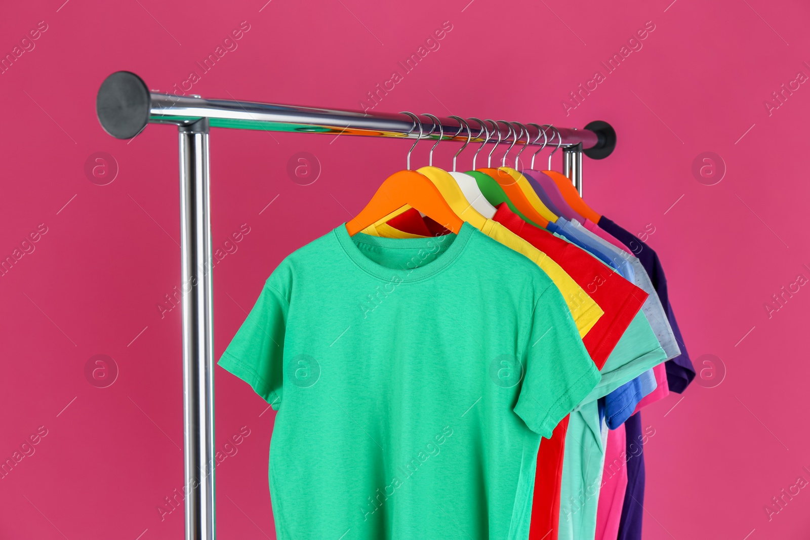 Rack with stylish children clothes on pink background Photo of Rack with stylish children clothes on pink background