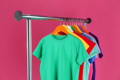 Rack with stylish children clothes on pink background Photo of Rack with stylish children clothes on pink background
