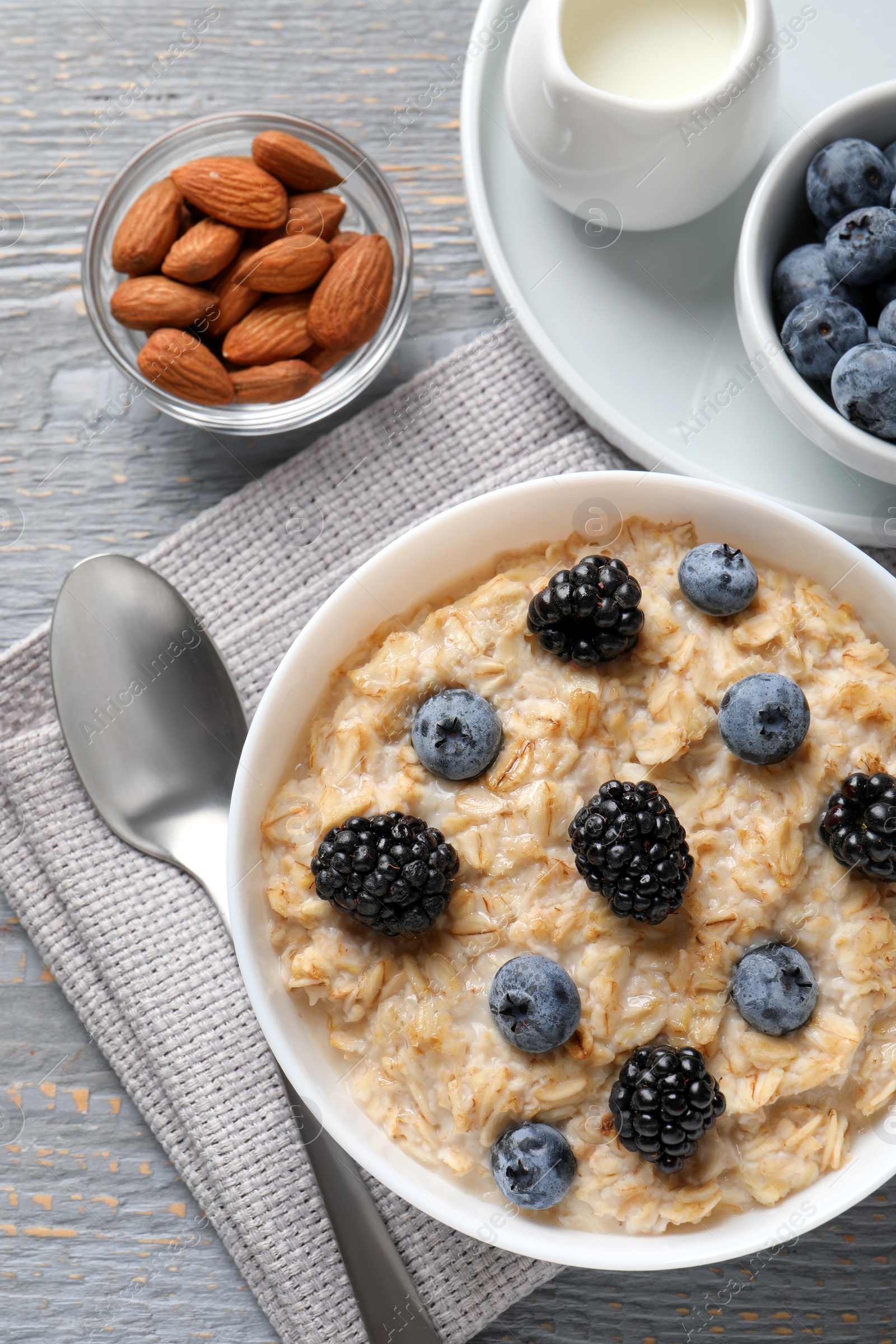 Tasty oatmeal porridge with blackberries and blueberries served on light grey wooden table, flat lay Photo of Tasty oatmeal porridge with blackberries and blueberries served on light grey wooden table, flat lay