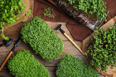 Fresh organic microgreens and gardening tools on wooden table, flat lay Photo of Fresh organic microgreens and gardening tools on wooden table, flat lay
